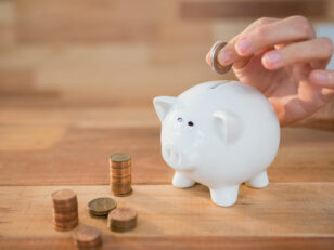 Hand inserting coin in piggy bank